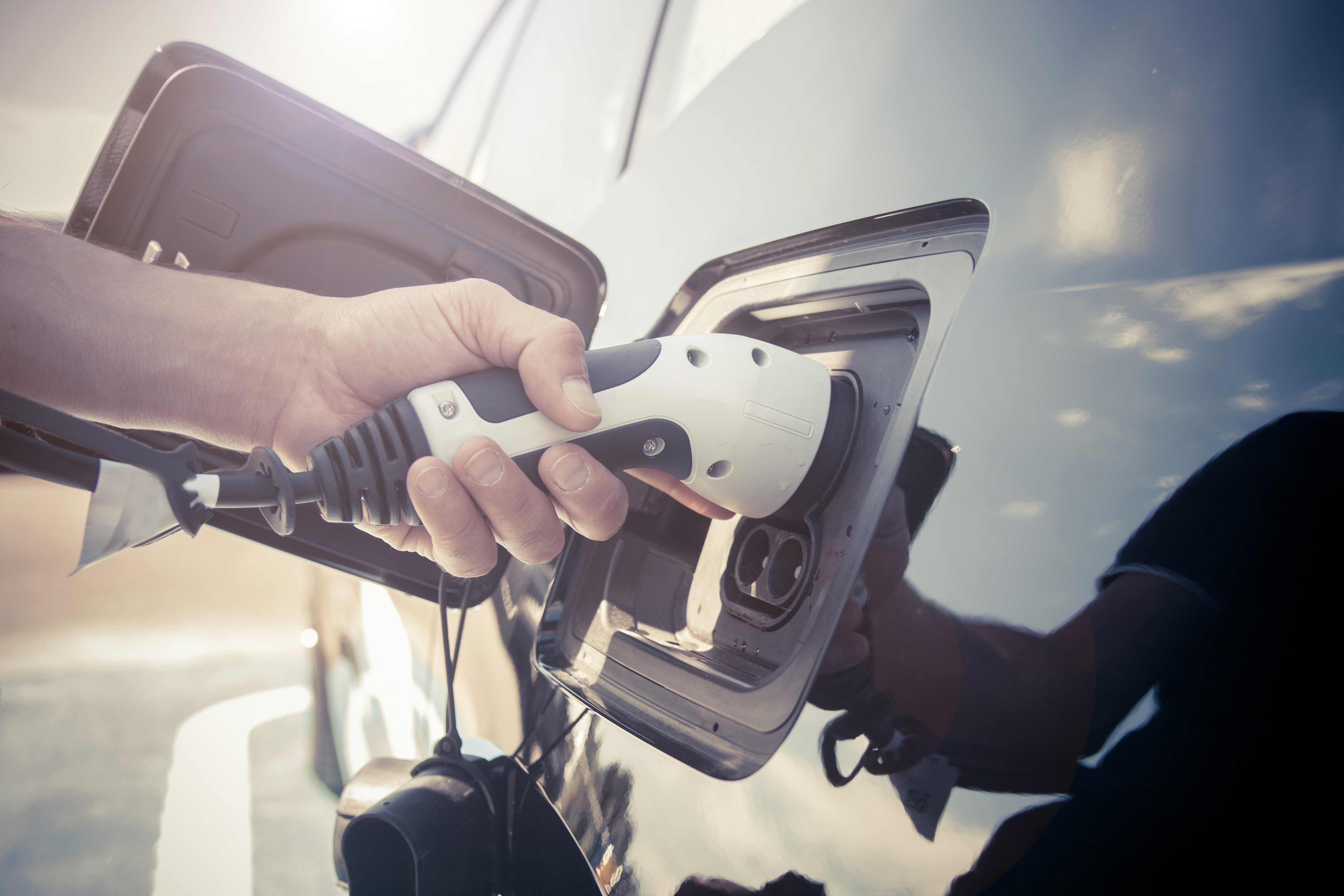 Bilde av en elbillader som blir plugget i bilen
